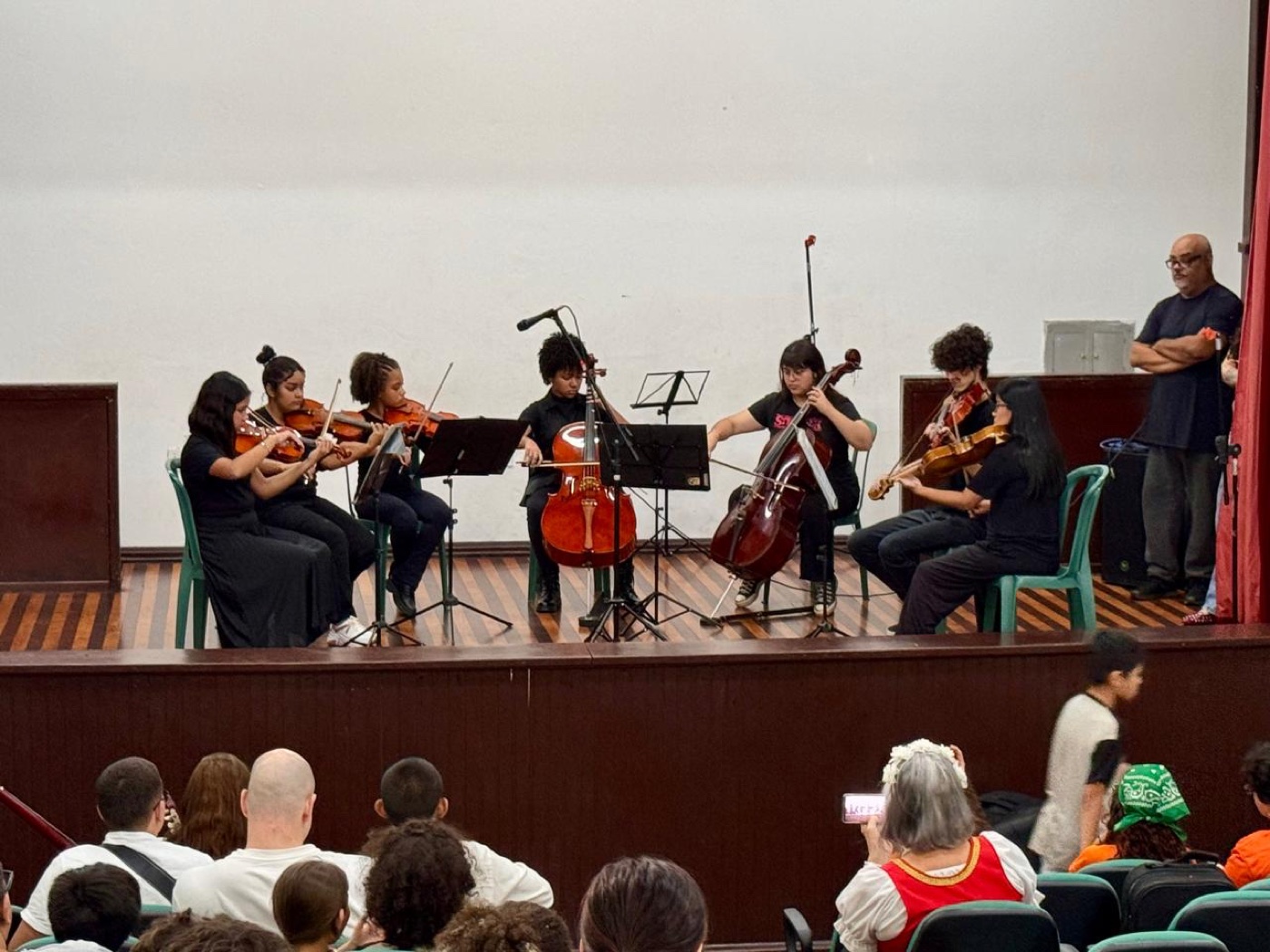 Alunos de cordas se apresentando em auditório