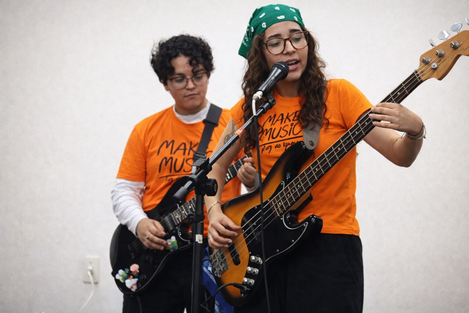 Músicas tocando baixo e guitarra com camisetas do Make Music